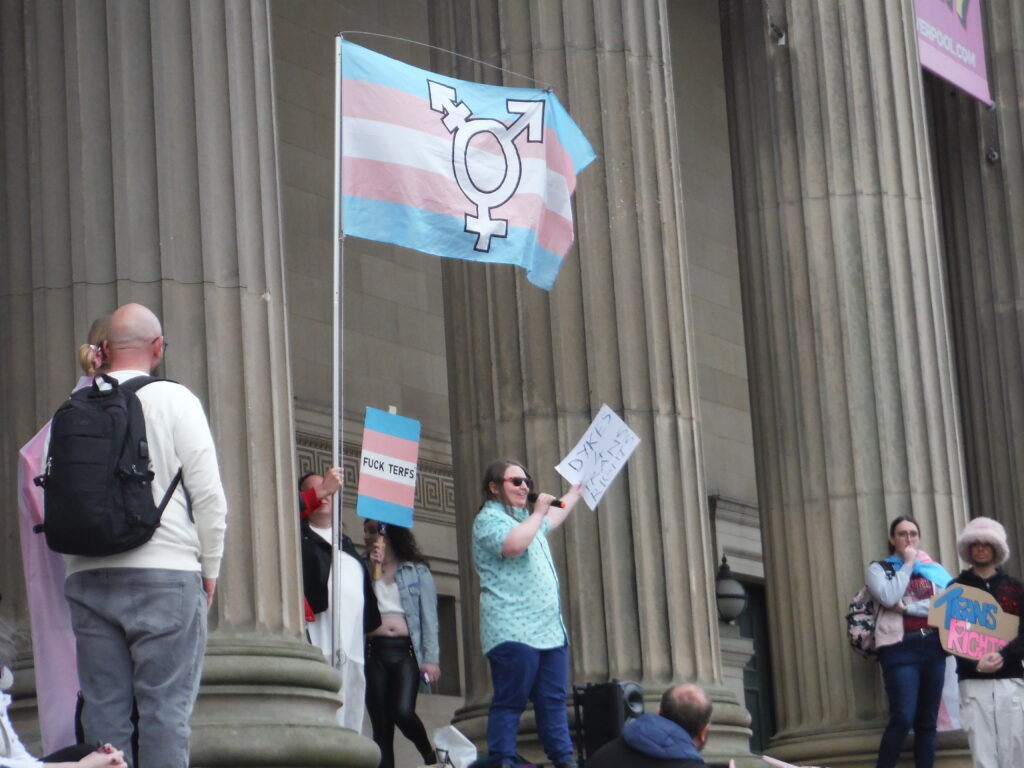 Photograph at a Trans Rights Demonstration in Liverpool. Sign held reading “DYKES 4 TRANS RIGHTS”